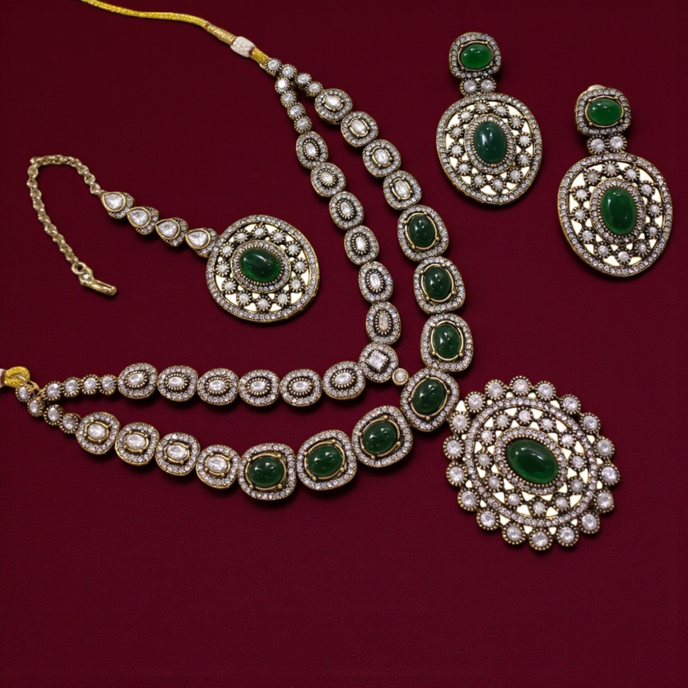 Traditional Indian Kundan jewelry set adorned with deep green gemstones and surrounded by white stones, comprising a matching necklace, earrings, pendant, and maang tikka.