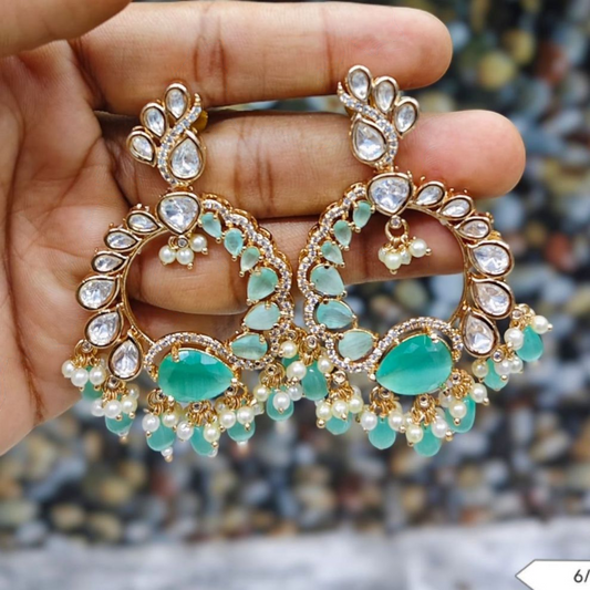 Ornate gold-tone chandelier earrings with white stones, pastel green gems, and pearl dangles in a traditional Indian semi-circular design.