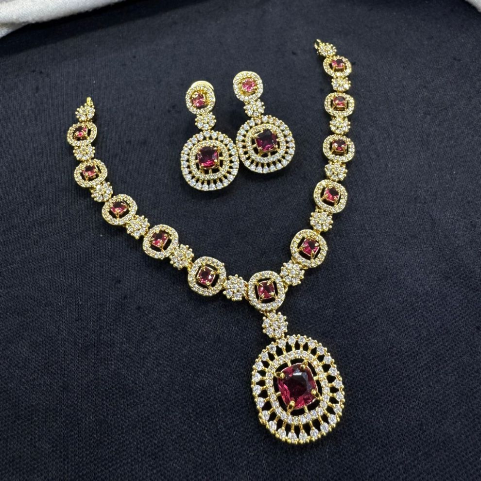 Royal gold necklace set featuring vivid ruby rani square stones surrounded by white crystals, accompanied by complementary earrings