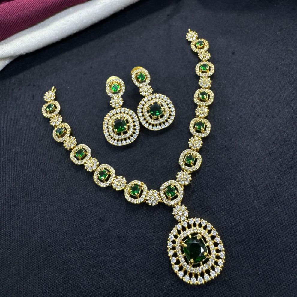 Luxurious gold and diamond necklace set showcasing deep emerald green stones, complete with matching circular drop earrings.