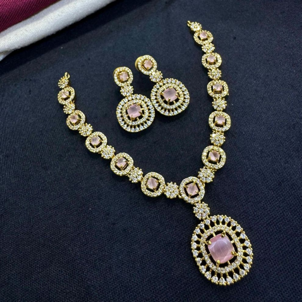 Sophisticated blush pink gemstone necklace set in a gold and diamond frame, with matching dual-layered earrings.